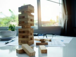 Planning, risk and strategy in business concept, businessman gambling placing wooden block on a tower with meeting background.vintage tone Retro filter effect,soft focus,low light.(selective focus)